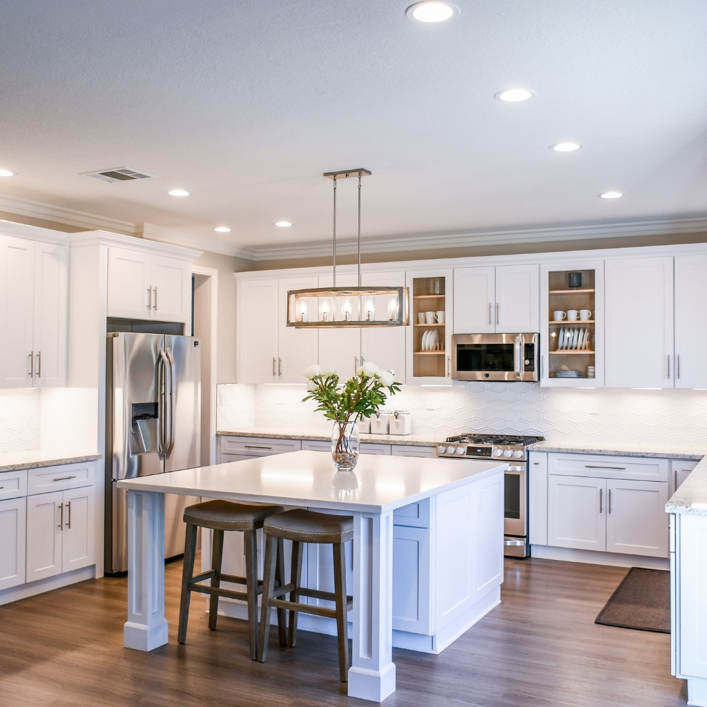 A pristine kitchen featuring white cabinets and a central island, showcasing a modern and organised cooking space.