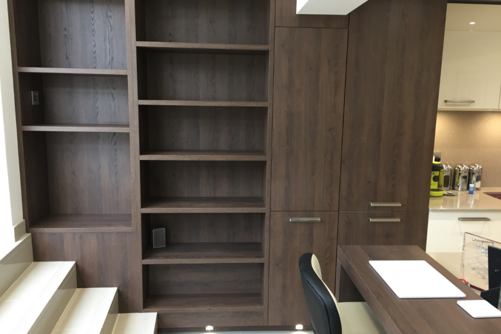 A cozy room featuring a wooden desk and a tall bookcase filled with books, creating a studious atmosphere.