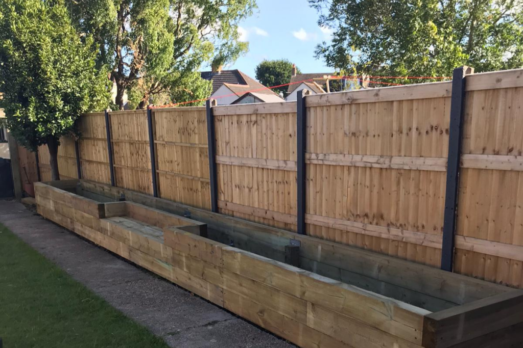 A wooden fence surrounds a central wooden planter, creating a rustic and inviting outdoor space.