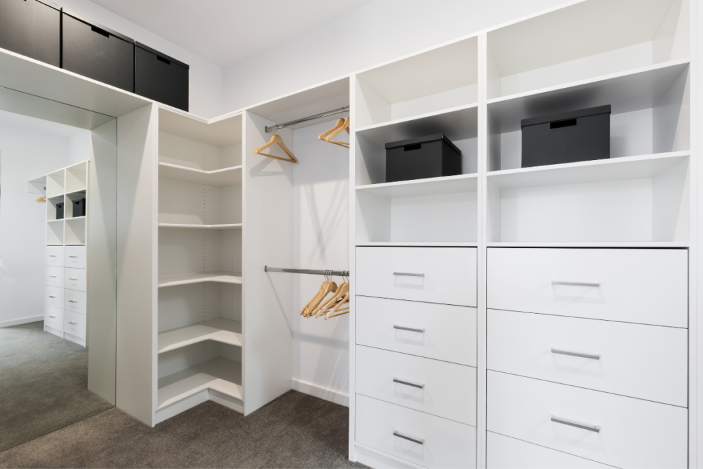 A spacious walk-in closet featuring elegant white cabinets and drawers, providing ample storage and organisation.