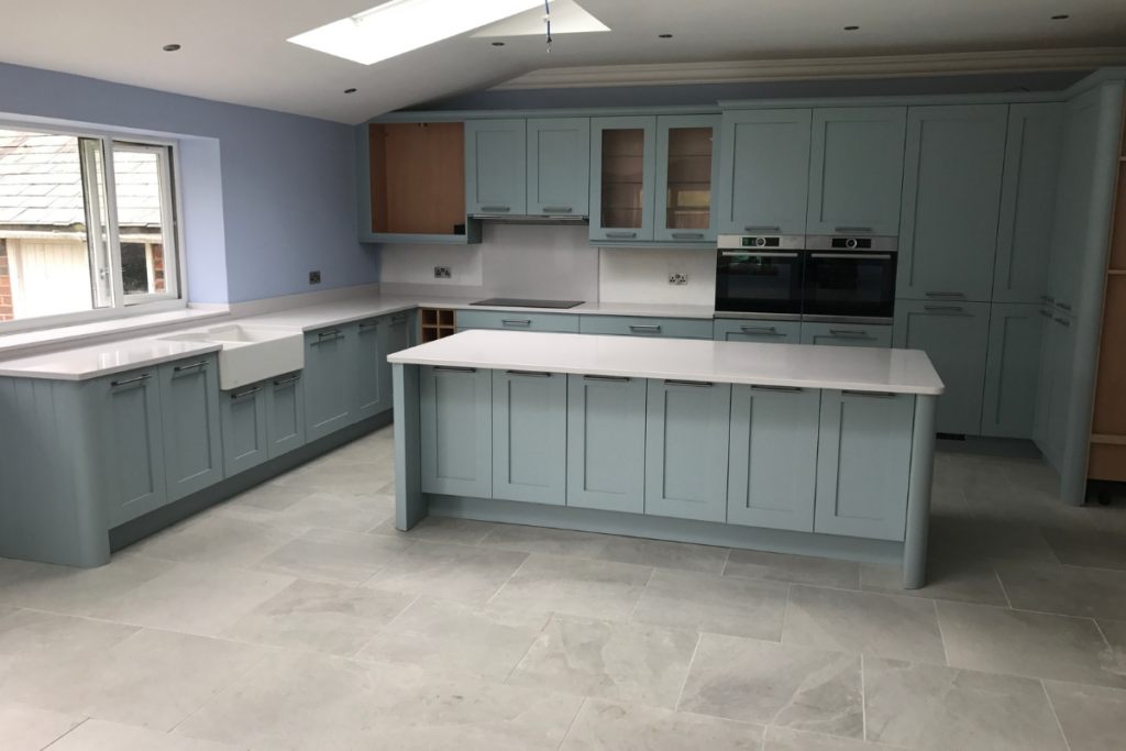 A bright kitchen featuring blue cabinets and a skylight, creating a cheerful and airy atmosphere.