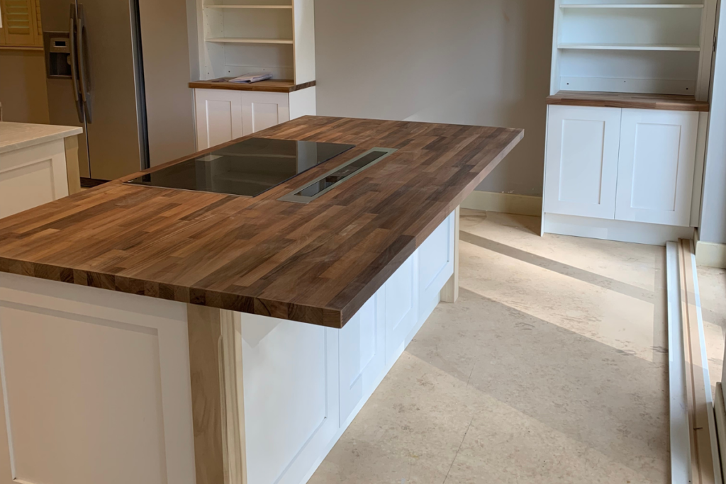 A kitchen island featuring a wooden top and sleek white cabinets, creating a modern and inviting cooking space.