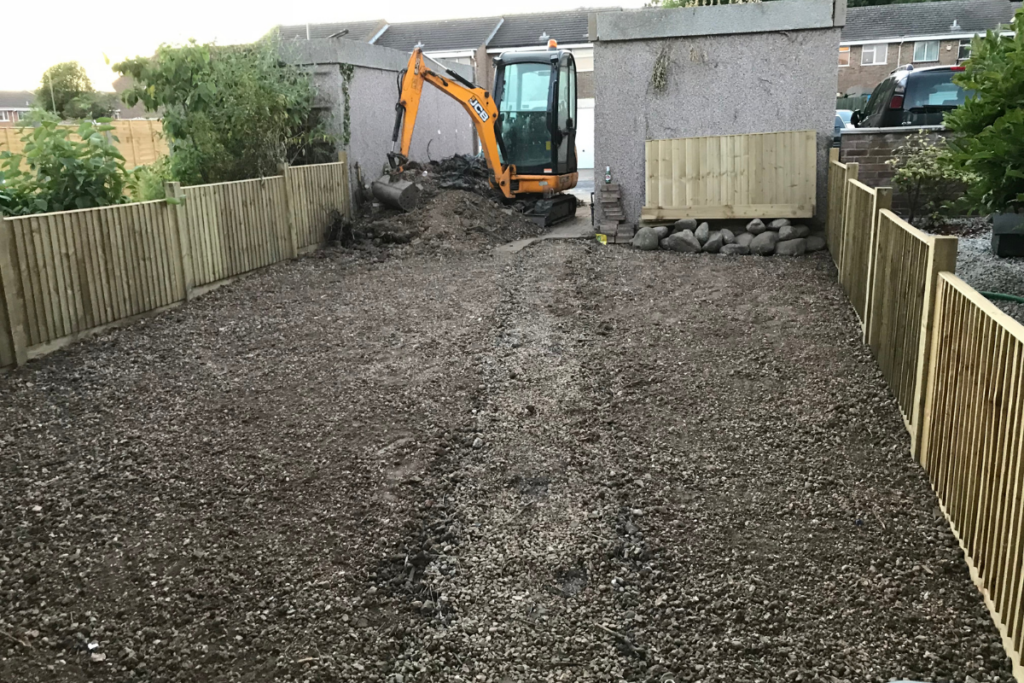 A digger excavates a hole in a yard, showcasing heavy machinery in action on a sunny day.