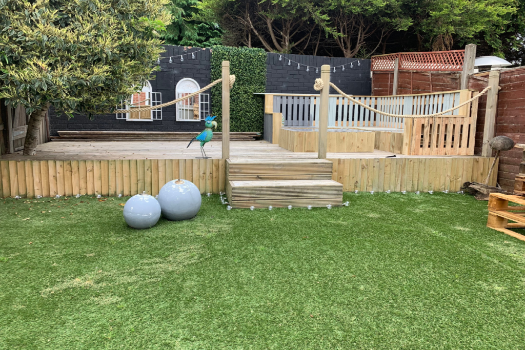 A cozy backyard featuring a wooden deck surrounded by a tall wooden fence, perfect for relaxation and outdoor gatherings.