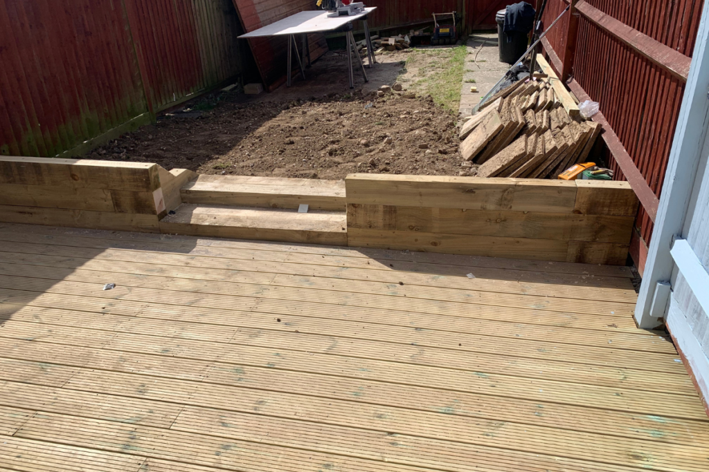 A wooden deck featuring a garden bed and a surrounding fence, creating a cozy outdoor space.