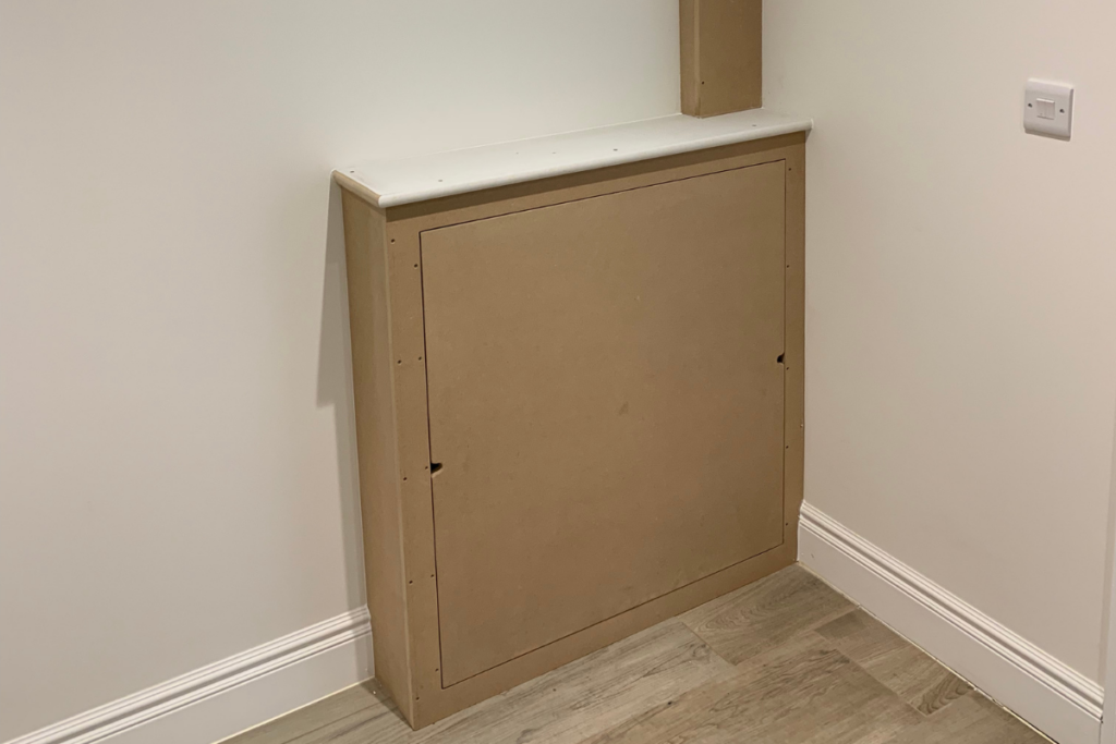 A small corner cabinet with a door, neatly placed in a cozy room setting.