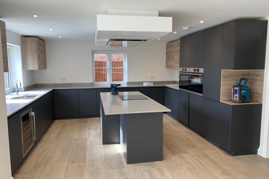 A spacious kitchen featuring a large island with a sink, surrounded by modern appliances and bright lighting.